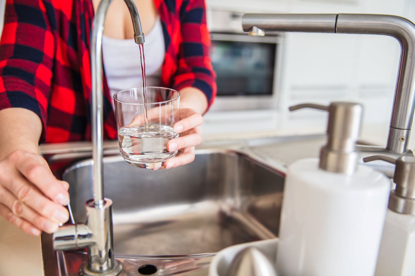 Person running tap water into a glass