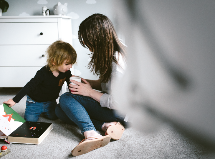 women holding cup sitting on floor with child