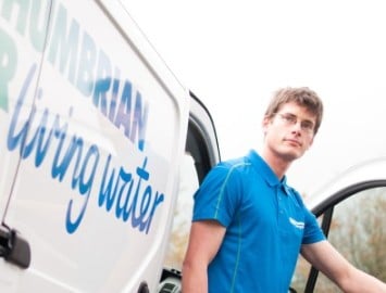 Northumbrian Water employee in blue polo shirt outside of van