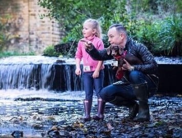 A Dad his daughter and dog by the riverbank