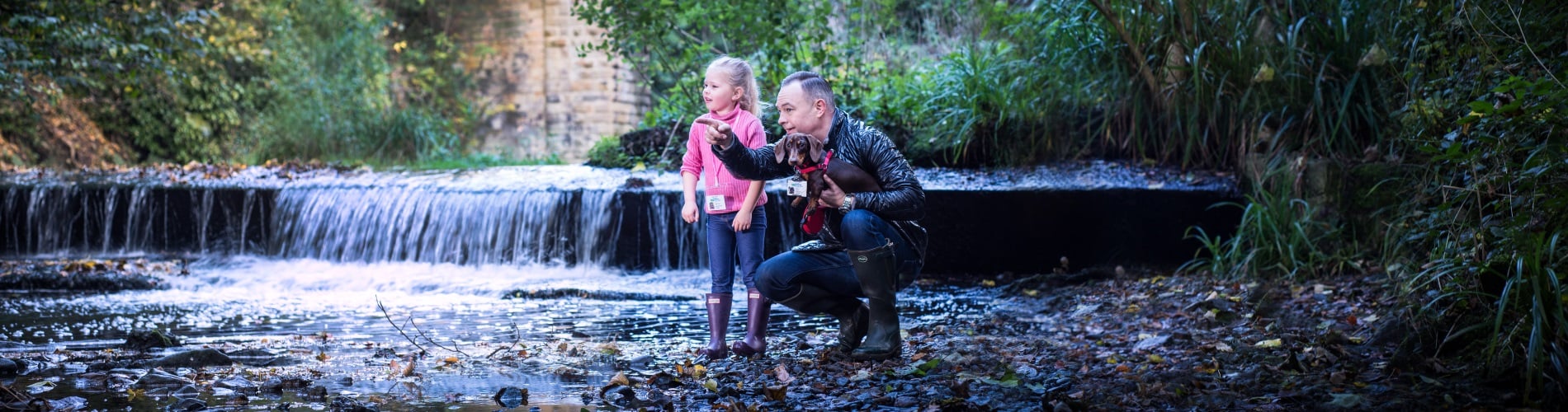 Man with daughter and dog next to a river