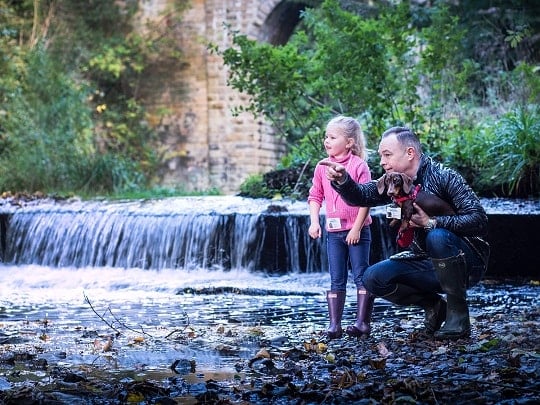 Man with daughter and dog next to a river